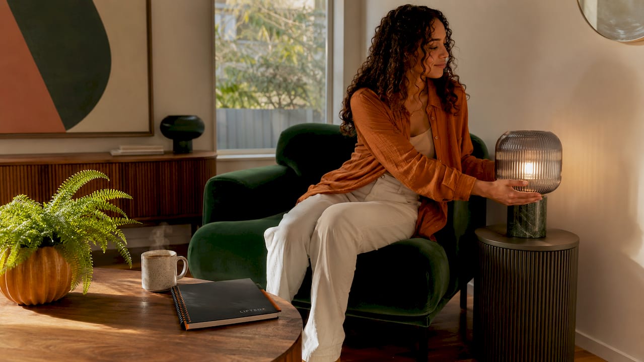 Woman adjusting warm LED lamp in living room