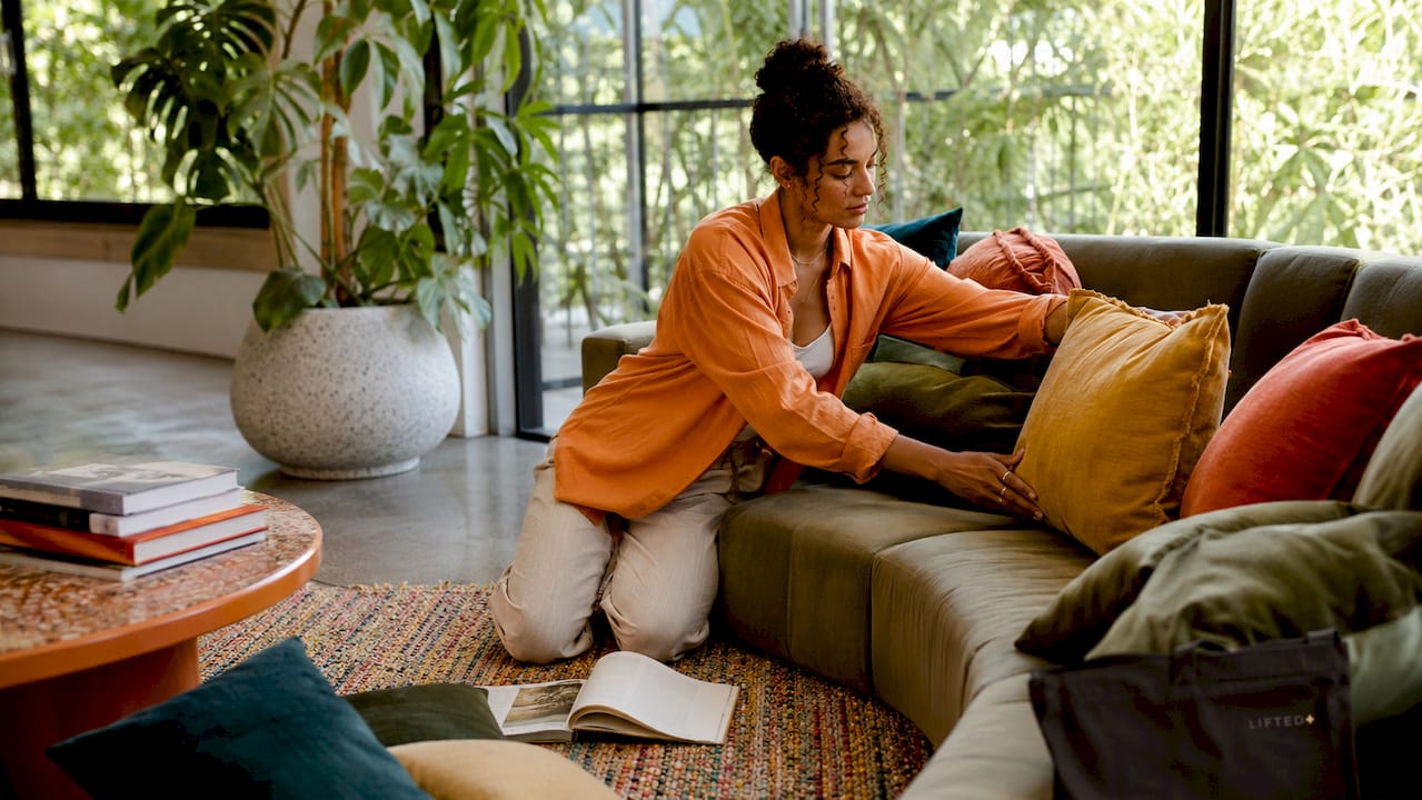 Woman arranging cushions in bright living room