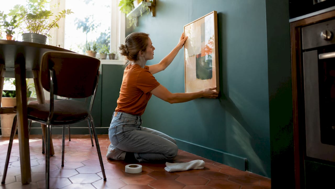 Woman applying damage-free wall art in rental