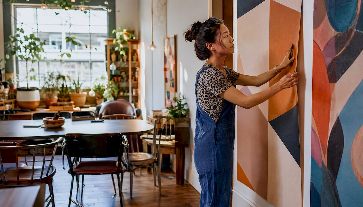 Woman applying removable feature wall wallpaper